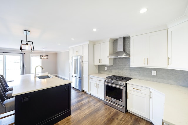 kitchen with a sink, wall chimney exhaust hood, appliances with stainless steel finishes, and backsplash