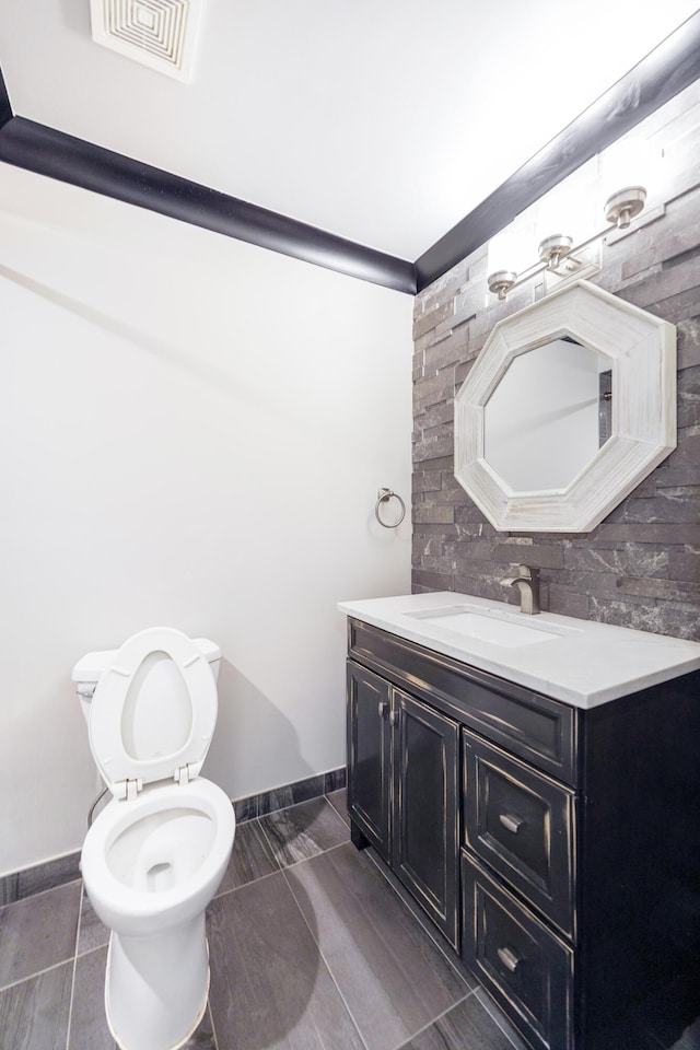 half bathroom featuring visible vents, tasteful backsplash, vanity, baseboards, and toilet