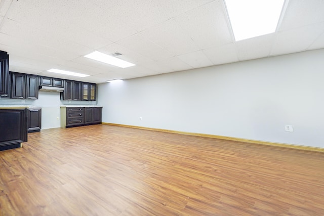 interior space featuring baseboards, visible vents, a paneled ceiling, and light wood-style floors