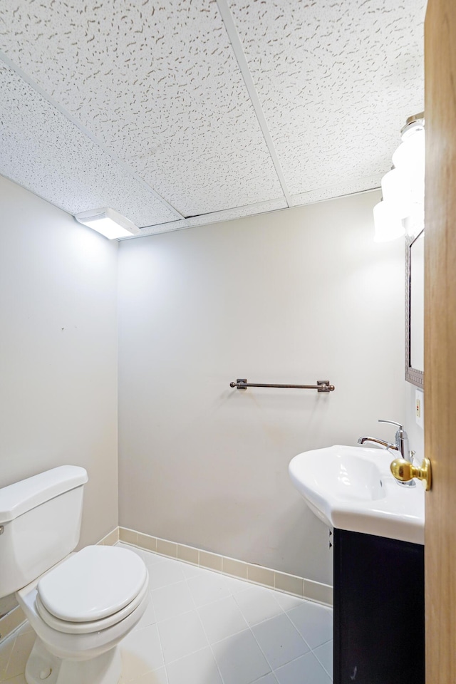 bathroom with vanity, baseboards, a drop ceiling, and toilet