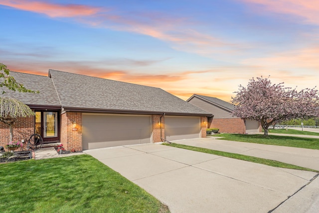 view of front of home with a lawn, an attached garage, concrete driveway, and brick siding