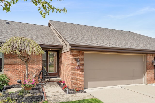 ranch-style home featuring a garage, concrete driveway, roof with shingles, and brick siding