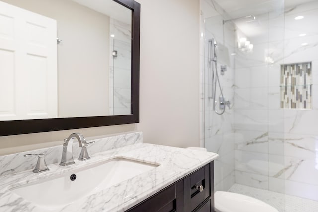 full bathroom with a marble finish shower, vanity, and toilet