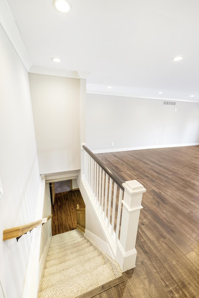 stairway featuring crown molding, recessed lighting, wood finished floors, and visible vents