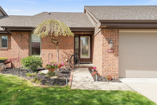 doorway to property featuring brick siding, a shingled roof, and a garage