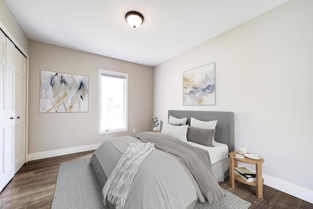 bedroom with a closet, baseboards, and dark wood finished floors