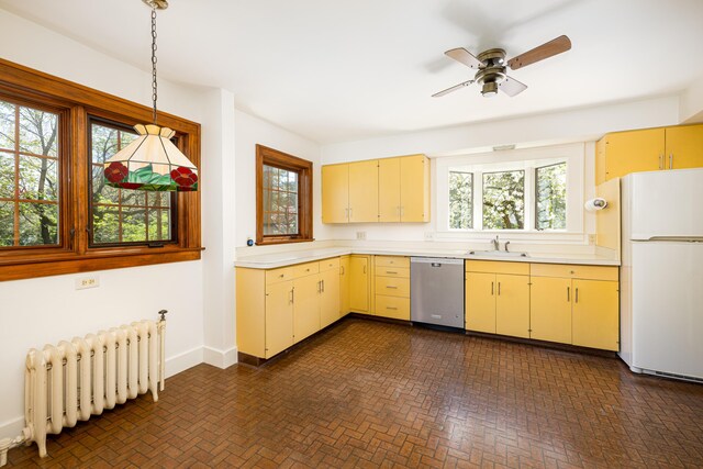 kitchen featuring stainless steel dishwasher, radiator heating unit, freestanding refrigerator, and light countertops