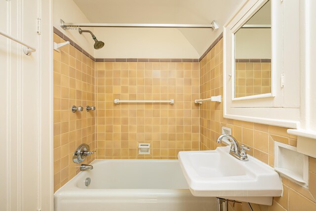 bathroom featuring backsplash, shower / bath combination, tile walls, and a sink