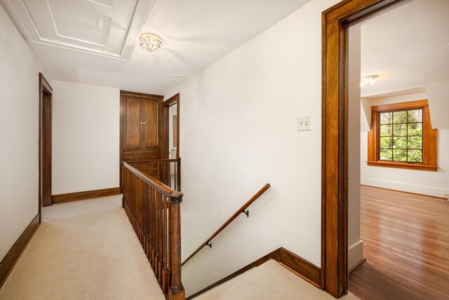 corridor featuring baseboards, an upstairs landing, and attic access