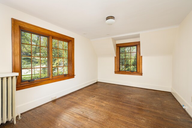 unfurnished room featuring baseboards, dark wood-style floors, and radiator