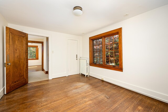 spare room featuring baseboards, radiator heating unit, and wood finished floors