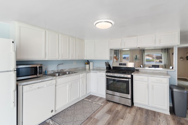 kitchen with stainless steel appliances, a sink, light countertops, and white cabinets