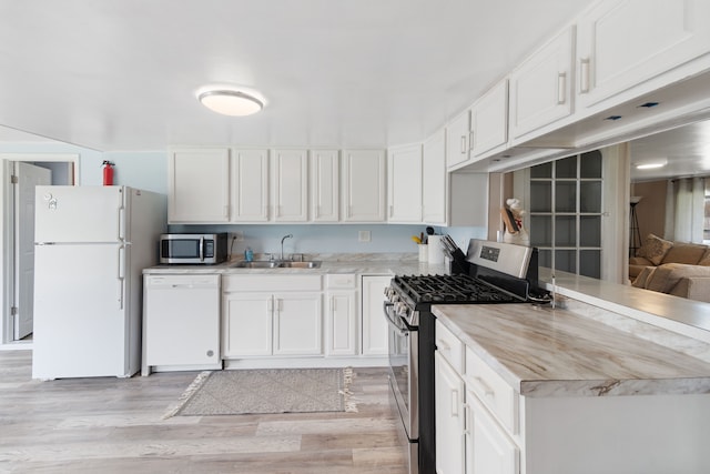 kitchen featuring appliances with stainless steel finishes, a sink, light countertops, white cabinets, and light wood-style floors