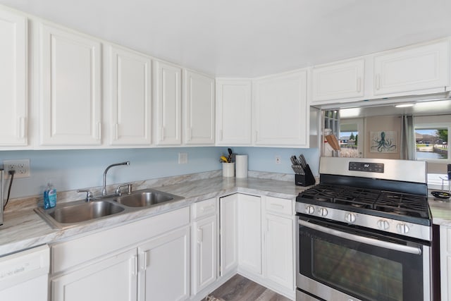 kitchen with stainless steel gas range oven, a sink, white dishwasher, white cabinetry, and light countertops