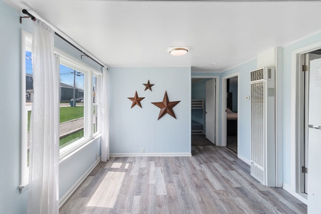 empty room featuring a heating unit, wood finished floors, and baseboards