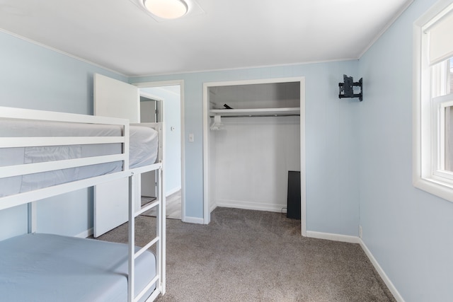 unfurnished bedroom featuring carpet, a closet, ornamental molding, and baseboards