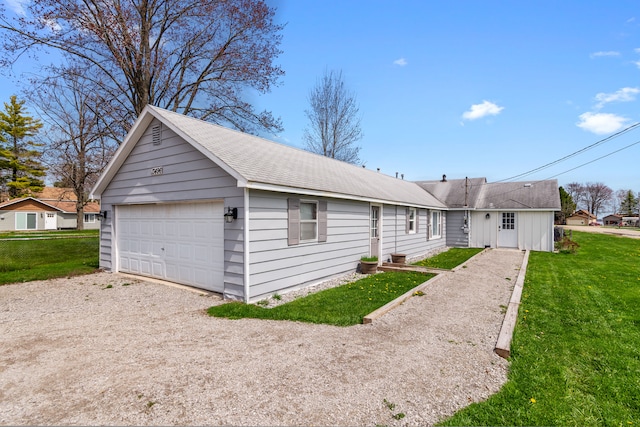 ranch-style house featuring a detached garage, a front lawn, and a shingled roof