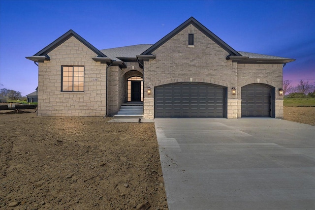 720 Marlayna Dr, Oxford, MI 48371 - french country inspired facade featuring driveway, roof with shingles, brick siding, an attached garage, and stone siding