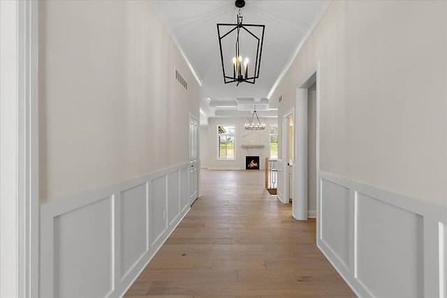 720 Marlayna Dr, Oxford, MI 48371 - corridor featuring a notable chandelier, a decorative wall, light wood-style flooring, a wainscoted wall, and visible vents