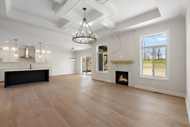 720 Marlayna Dr, Oxford, MI 48371 - unfurnished living room featuring an inviting chandelier, light wood-style flooring, visible vents, and a high end fireplace