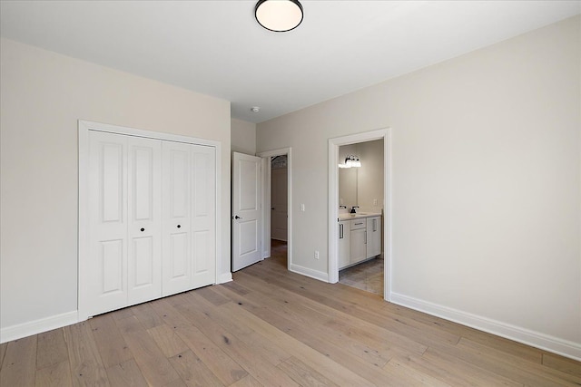 720 Marlayna Dr, Oxford, MI 48371 - unfurnished bedroom featuring a closet, baseboards, ensuite bathroom, and light wood-style floors