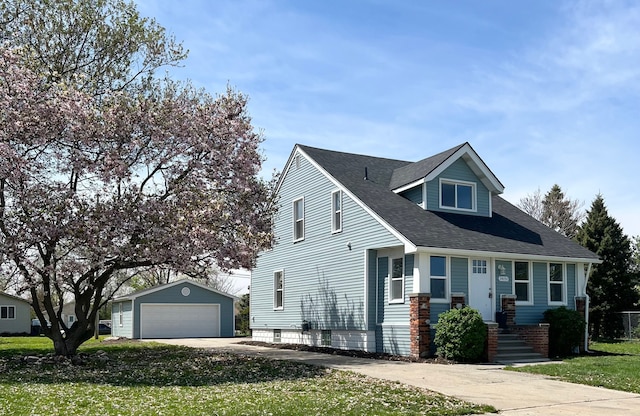view of front of property with an outdoor structure, roof with shingles, a front yard, and a detached garage