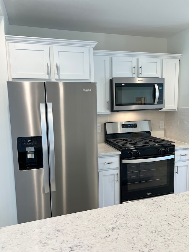 kitchen featuring light stone counters, decorative backsplash, white cabinetry, and appliances with stainless steel finishes
