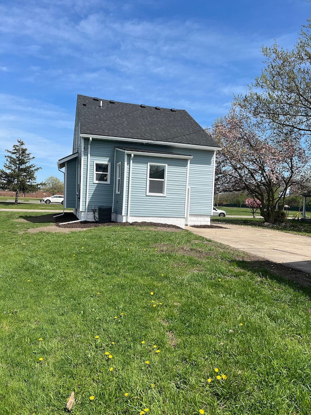exterior space featuring a lawn, roof with shingles, and central AC