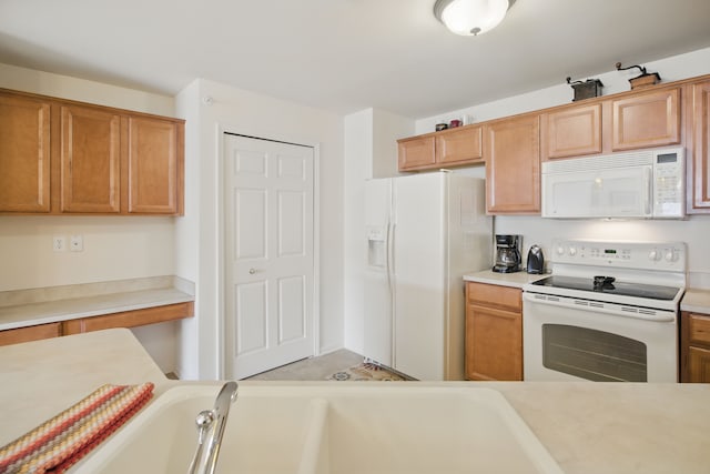 kitchen featuring white appliances, brown cabinetry, and light countertops