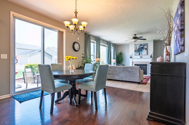 1813 Garfield St, Howell, MI 48855 - dining space featuring a chandelier, dark wood-type flooring, a ceiling fan, a glass covered fireplace, and baseboards