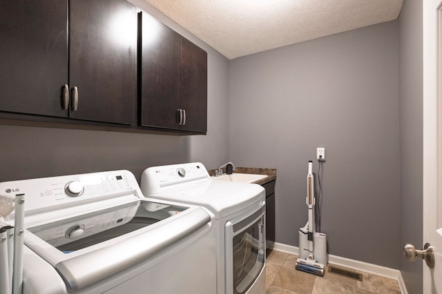 1813 Garfield St, Howell, MI 48855 - laundry room with washing machine and clothes dryer, cabinet space, baseboards, a textured ceiling, and light tile patterned floors