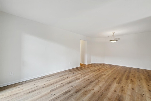 empty room featuring baseboards, light wood-style flooring, and visible vents