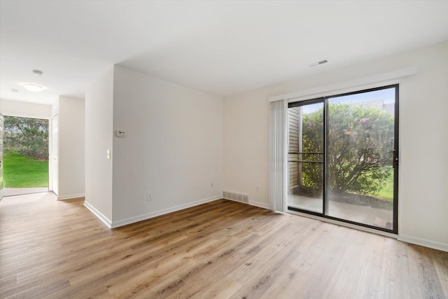 empty room featuring baseboards, visible vents, and wood finished floors