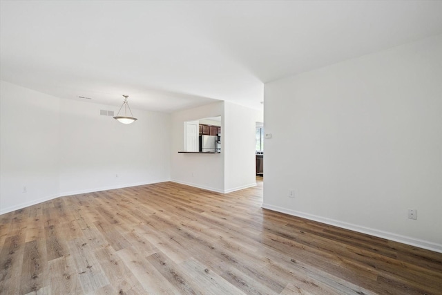 unfurnished living room with light wood finished floors, visible vents, and baseboards