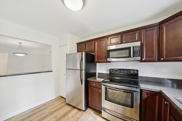 kitchen featuring pendant lighting, stainless steel appliances, baseboards, and light wood-style floors