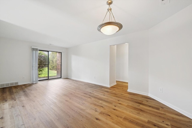 spare room featuring baseboards, visible vents, and wood finished floors