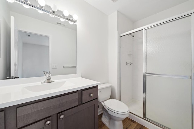 full bath featuring a stall shower, toilet, visible vents, vanity, and wood finished floors