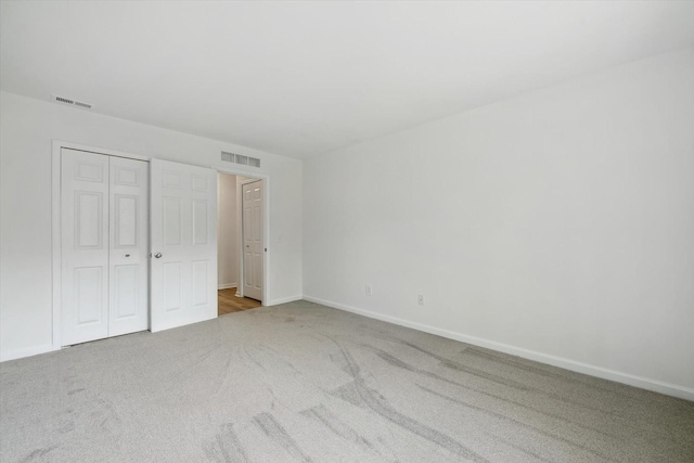 unfurnished bedroom with a closet, visible vents, baseboards, and carpet floors