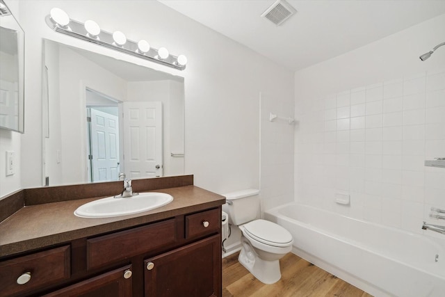 bathroom featuring toilet, wood finished floors,  shower combination, visible vents, and vanity