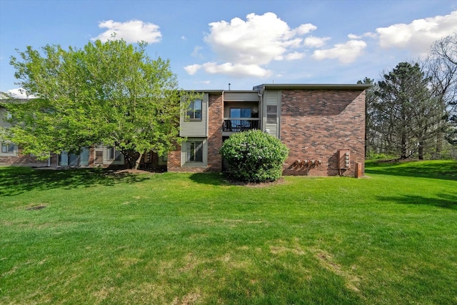 back of house featuring brick siding and a lawn