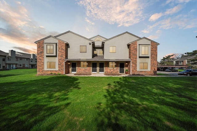rear view of property with a yard and brick siding
