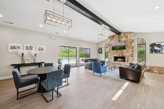 dining room with wood finished floors, visible vents, recessed lighting, a stone fireplace, and vaulted ceiling with beams