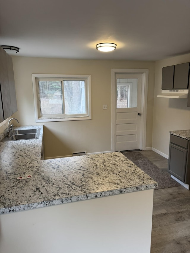 8854 E Pickard Rd, Mount Pleasant, MI 48858 - kitchen with light stone countertops, a sink, dark wood finished floors, a peninsula, and gray cabinetry