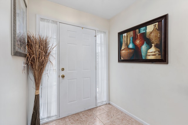 foyer entrance with light tile patterned floors and baseboards