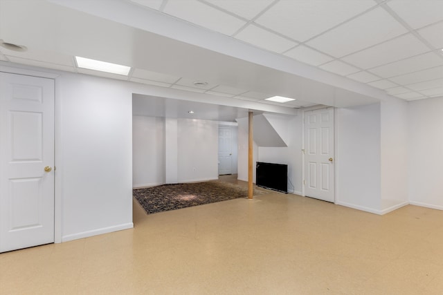 finished basement featuring baseboards, tile patterned floors, and a drop ceiling