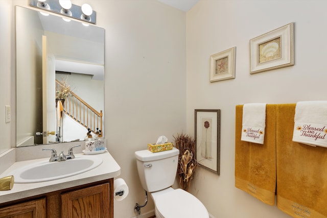 half bath featuring vanity, baseboards, and toilet
