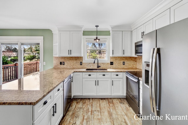 kitchen with a peninsula, white cabinetry, a sink, light wood finished floors, and appliances with stainless steel finishes