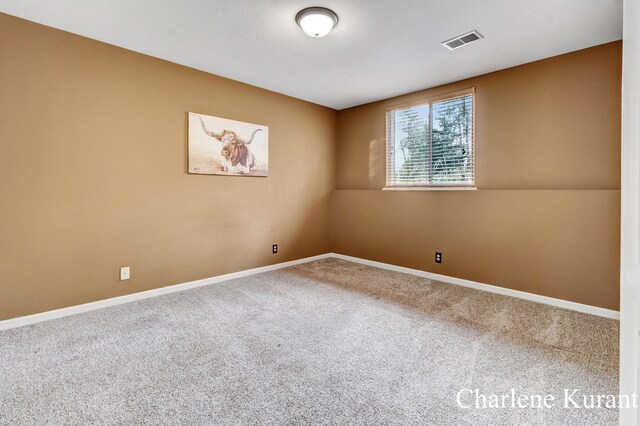 carpeted empty room featuring visible vents and baseboards