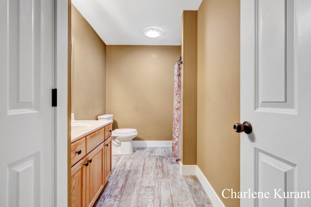 full bathroom with vanity, toilet, a shower with shower curtain, baseboards, and wood finished floors