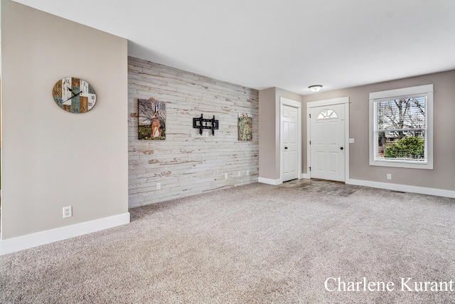 foyer with carpet floors, baseboards, and an accent wall